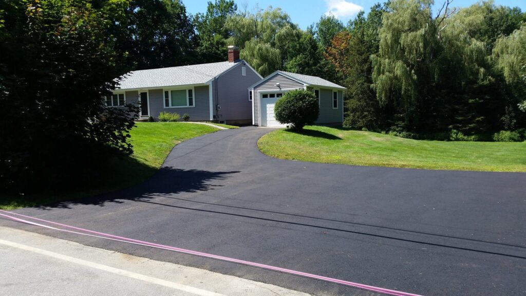 Newly paved residential asphalt driveway curving up to a single-family home
