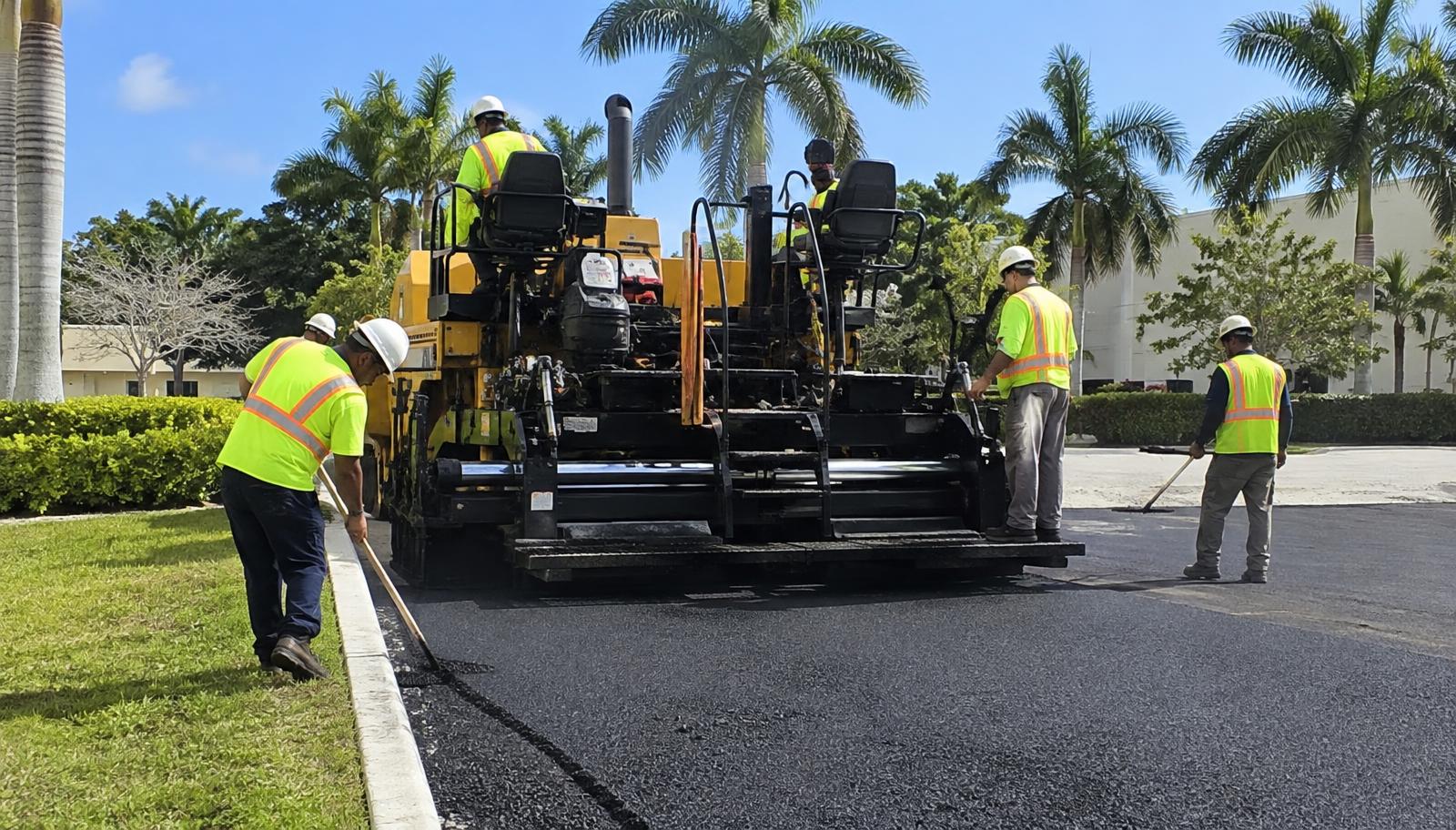 Paving crew laying fresh asphalt on a commercial parking lot